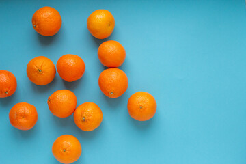 Many fresh orange fruits on light blue background. Vibrant horizontal photo of citrus food with copy space top view