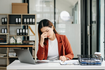 Woman who is tired and overthinking from working with tablet and laptop at modern office.