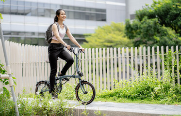 Confident 20s businesswoman ride bicycle outside to office in downtown. Environmentalist commuting by cycling reduce carbon footprint. Bike to work eco friendly alternative vehicle to global warming.