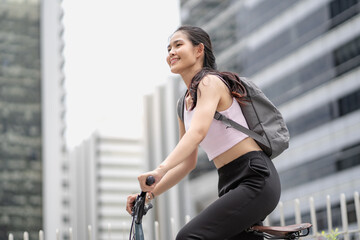 Confident 20s businesswoman ride bicycle outside to office in downtown. Environmentalist commuting by cycling reduce carbon footprint. Bike to work eco friendly alternative vehicle to global warming.