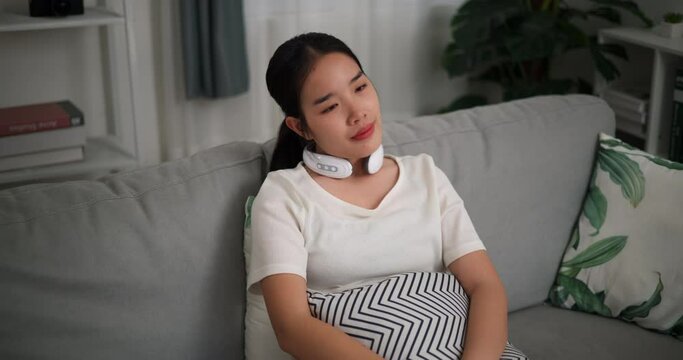 Footage dolly shot, Relaxed young woman wear automatic massage neck at home with eyes closed, relaxing body and mind alone in the living room, breathing fresh air,