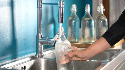 Filling a glass or glass bottle with water from the kitchen tap at home - quality of drinking water...