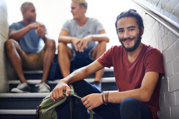 Portrait, stairs and student with smile, backpack and together with classmates as friends for conversation. University, school and man in course with scholarship, campus and people relax on steps