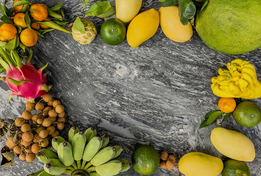 Assorted exotic fruits including dragon fruit, mangoes, and bananas arranged on a textured grey stone background, perfect for healthy lifestyle themes with copy space for text