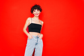 Young beautiful smiling female in trendy summer black tank top and jeans. Carefree woman posing...