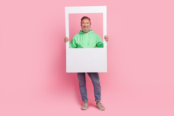 Full length photo of handsome senior man hold instant photo frame dressed stylish green garment...