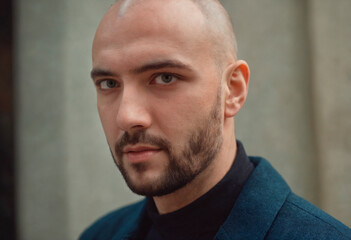 Obraz premium A bald-headed man dressed in a sharp blue suit stands confidently, his hands in his pockets. He exudes a professional and polished appearance.