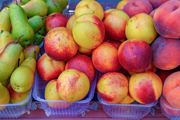 Freshly picked peaches at the outdoor farmers market in selective focus. Fruit background.Sale of healthy and wholesome food. Harvest concept.