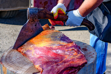 Fresh raw steak meat in selective focus being cut by with an ax at the market.Sale of pieces of pork and beef.