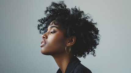 A fashion portrait of a beautiful young African American woman with curly hair against a gray background - obrazy, fototapety, plakaty