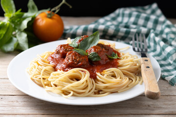 Spaghetti with meatballs on wooden table and black background