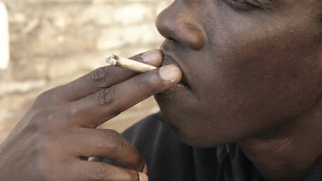 close up on the mouth of a young african man who eagerly smokes a cigarette