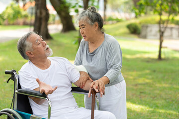 senior man sitting on a wheelchair and distorted face beside senior woman in the park