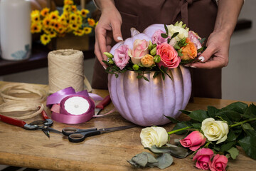 Florist makes an arrangement of pumpkins and flowers