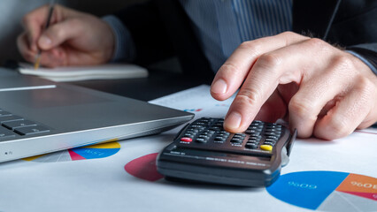 Concept of planning deductions, deduction of expenses, taxes. Businessman presses a calculator to...