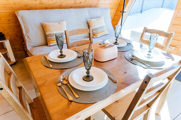 Wooden dining table set with plates and glasses, part of furniture in a house