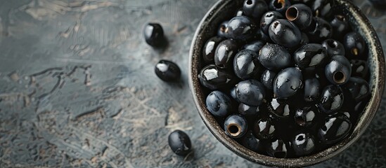 A bowl filled with deliciously satisfying black olives is placed on top of a table. The olives are piled high, ready to be enjoyed as a snack or added to various dishes.