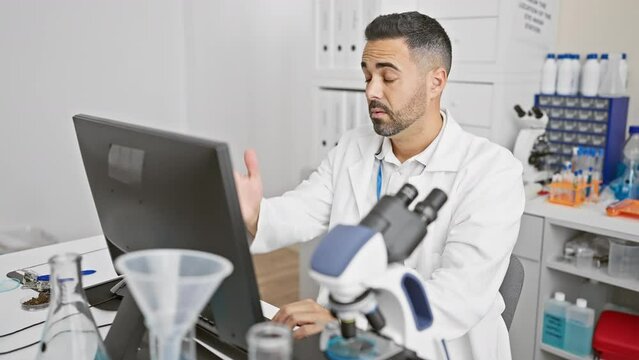 Oops! frustrated young hispanic man in scientist uniform, hand on head in despair, forgot a crucial error on the computer, a memory blunder in the lab