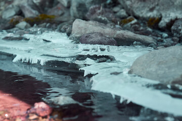 Ice and rocks by a stream of water in the mountains