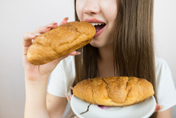 young beautiful girl eating a croissant, close-up, crop photo. female mouth eating croissant
