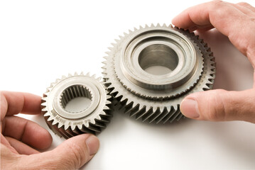 Male hands connecting two gears on white background, close-up.