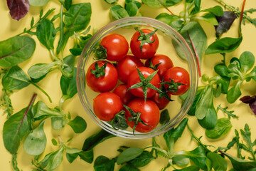 A bowl of cherry tomatoes with green leaves natural food on a table