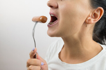 Naklejka premium Close-up of a woman eating a sausage.