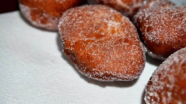 Homemade Berliners deep-fried with a sugar coating on a white cloth in moving light. Sweet brown German delicacy. Carnival tradition