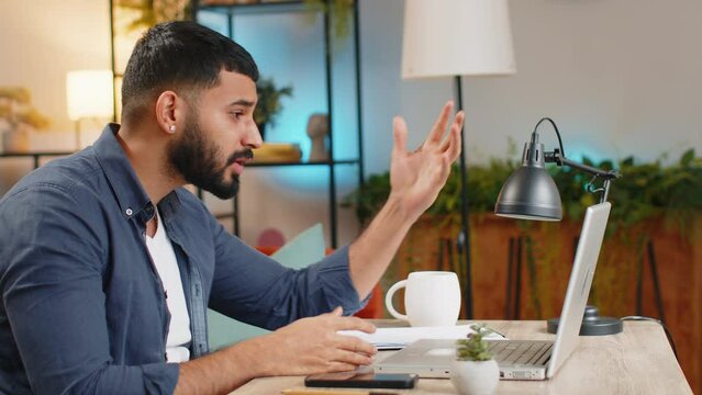 Conflict quarrel negotiation. Angry Indian freelancer man making webcam laptop online video call at home office. Upset mad manager talking conversation analyzing financial report mistake problem.