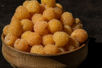 Yellow raspberries in a wooden bowl on the table. Summer berries background. Vitamin food, berry harvest. Healthy nutrition.