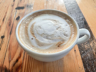Close up of a coffee cup with foam: Cappuccino, Latte, Flat White, Macchiato, Mocha on a wooden table	
