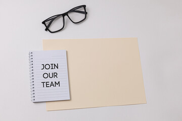 Notebook with Join our team text is on top of white office desk table with black glasses