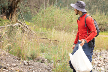 mountaineer with hat picking up garbage in nature