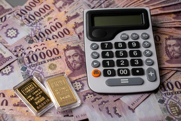 Hungarian forint banknotes are spread out and sorted on a table, with gold bars next to a...