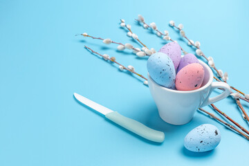 Cup with colored Easter eggs on the blue background.