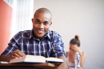 Classroom, university student and black man with smile, portrait and reading textbook for studying....