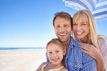 Portrait, smile and family at beach with umbrella, mockup space and tropical holiday adventure together. Happy mother, father and daughter on ocean vacation with blue sky, sunshine and island at sea