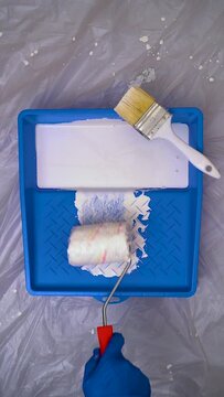 Paint Roller With White Paint Into a Blue Paint Tray on Protected Background, Vertical Video