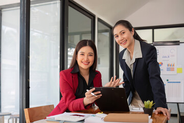 Two businesswomen discussing project strategy in office conference room Businesswoman discusses project planning with colleagues in modern workplace, gives advice on financial data report