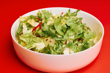 mixed green salad in a bowl on a red background