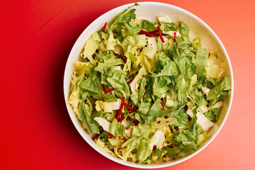 mixed green salad in a bowl on a red background