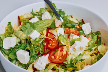 mixed green salad with tomatoes and cheese in a bowl.