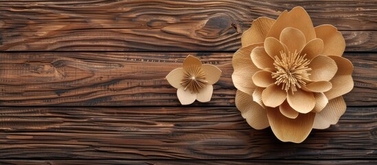 A paper flower placed on a wooden background creates an intriguing blend of textures and colors. The delicate petals of the flower stand out against the rugged surface of the wood.