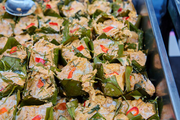 Steamed fish with curry paste wrapped with banana leaf in plate on table