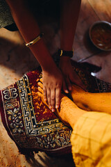 Haldi ceremony in Indian weddings. Haldi paste being smeared on the bride's feet in dramatic...