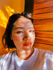 Cute Asian woman with bright make-up with sun dogs on face against yellow wall. Pretty Korean girl selfie picture. Soft focus. film grain pixel texture. Defocused. Japanese female. Chinese person.