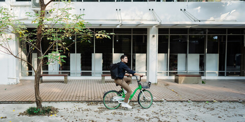 Elegant entrepreneur in smart casual cycling on bicycle track in warm sunny day area of city