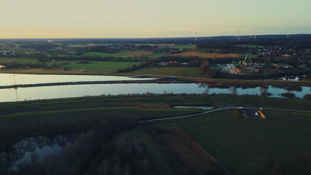 Winter sunset aerial drone view landscape navigable canal with bridges, agricultural fields and forests and farmers houses in Germany countryside. High quality 4k footage