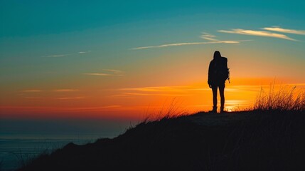 a person standing on a hill with a sunset in the background