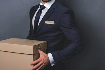 Cropped image of handsome businessman in formal wear holding a box with his stuff, on gray background. Generative AI